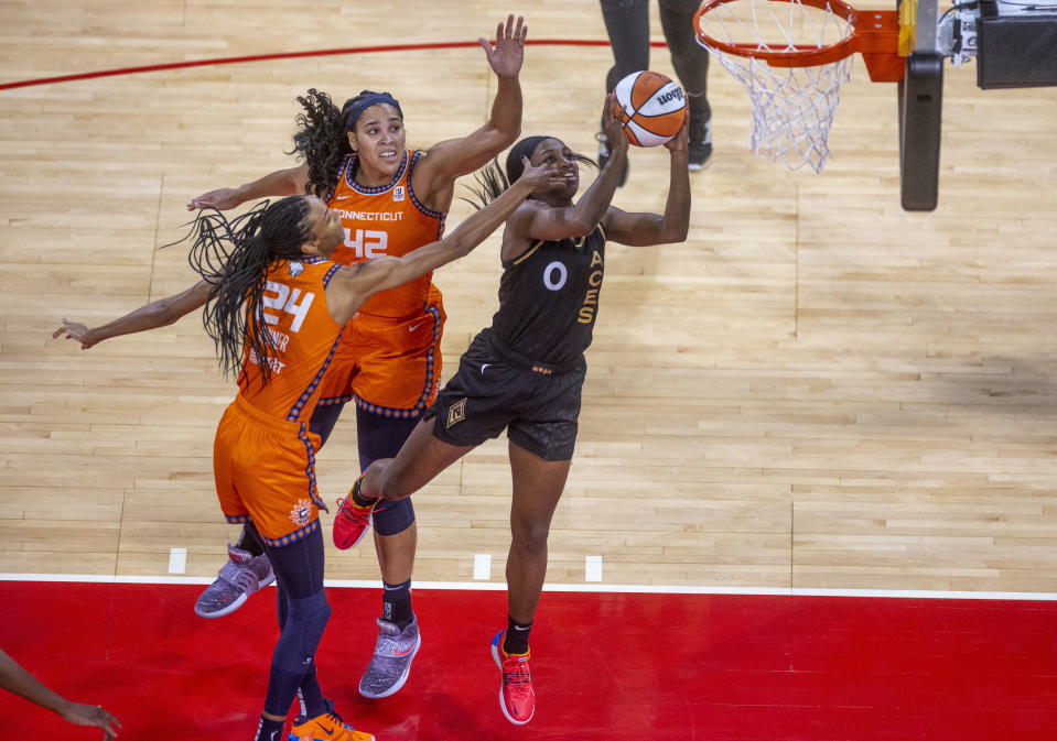 Las Vegas Aces guard Jackie Young (0) gets inside of Connecticut Sun center Brionna Jones (42) and forward DeWanna Bonner (24) for a basket during the first half in Game 1 of a WNBA basketball final playoff series Sunday, Sept. 11, 2022, in Las Vegas. (AP Photo/L.E. Baskow)