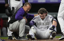 Colorado Rockies trainer Heath Townsend, left, helps Brendan Rodgers after he was hit by a pitch in the helmet by Washington Nationals starting pitcher Josiah Gray in the first inning of a baseball game Monday, Sept. 27, 2021, in Denver. (AP Photo/David Zalubowski)