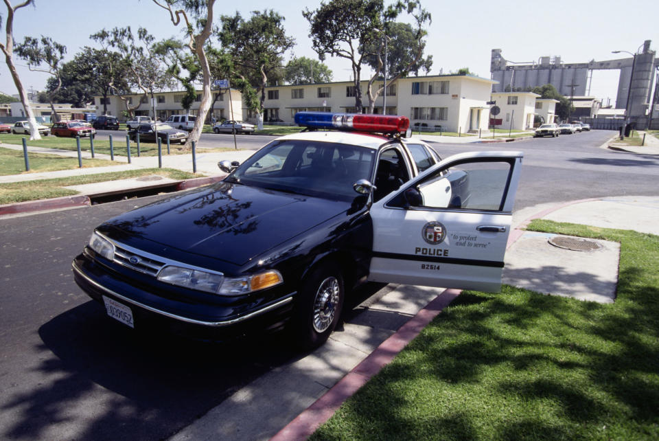 Police car with open door parked outside a building