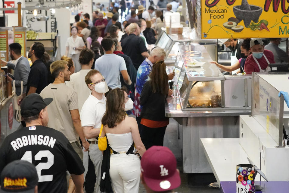 Mask an unmasked patrons walk along a row of food stands inside Grand Central Station Wednesday, July 13, 2022, in Los Angeles. Los Angeles County might be imposing a mandate on July 29 if COVID-19 numbers continue to rise. (AP Photo/Marcio Jose Sanchez)