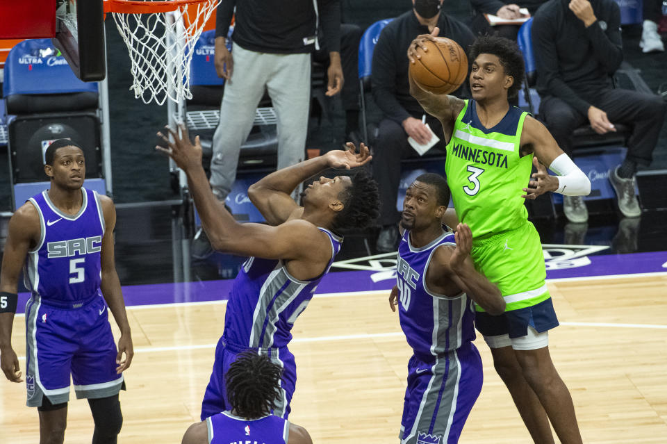 Minnesota Timberwolves forward Jaden McDaniels (3) pulls down a rebound over Sacramento Kings' Harrison Barnes (40) during the first quarter of an NBA basketball game in Sacramento, Calif., Tuesday, April 20, 2021. (AP Photo/Randall Benton)