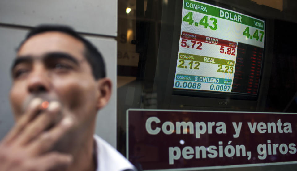 A security worker smokes outside a money exchange house showing a sign with the official government-set exchange rate of 4.47 Argentine pesos per 1 U.S. dollar in Buenos Aires, Argentina, Wednesday, May 16, 2012. The AFIP tax collection agency's recent measure to control and approve every currency exchange operation in the country has made it practically impossible for Argentines to buy dollars, forcing them to get the currency on the black market. (AP Photo/Natacha Pisarenko)