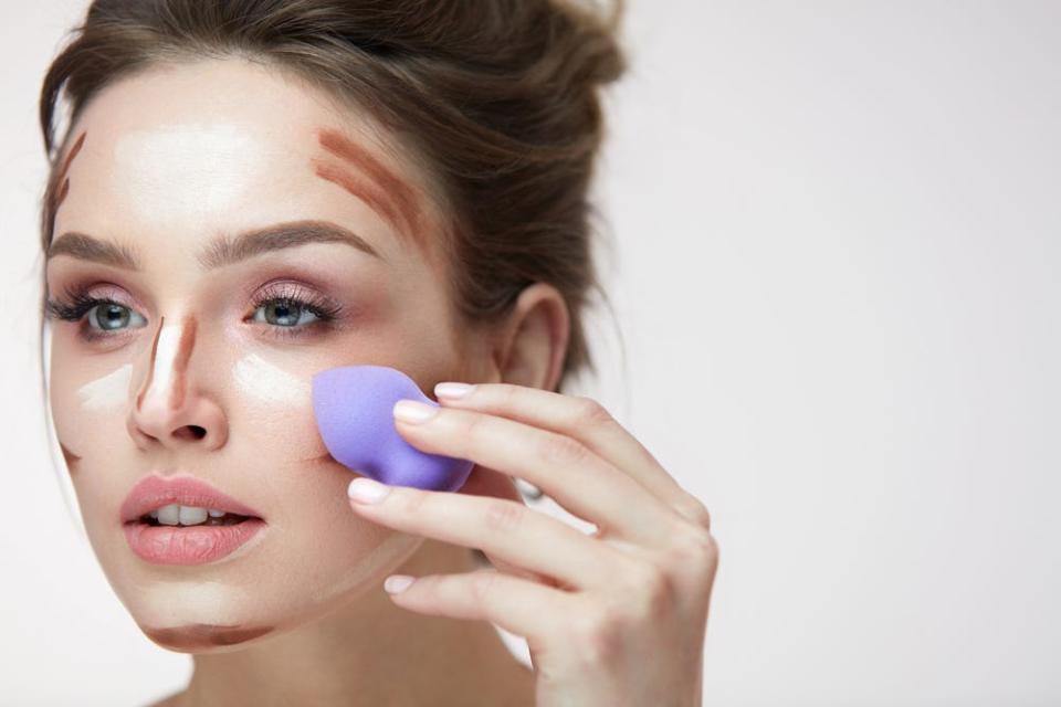 A woman applies makeup with a beauty blender