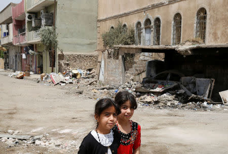 Iraqi children walk past a damaged buildings after the end of the battles between the Iraqi forces and Islamic State militants at their district in western Mosul, Iraq, April 30, 2017. REUTERS/Muhammad Hamed