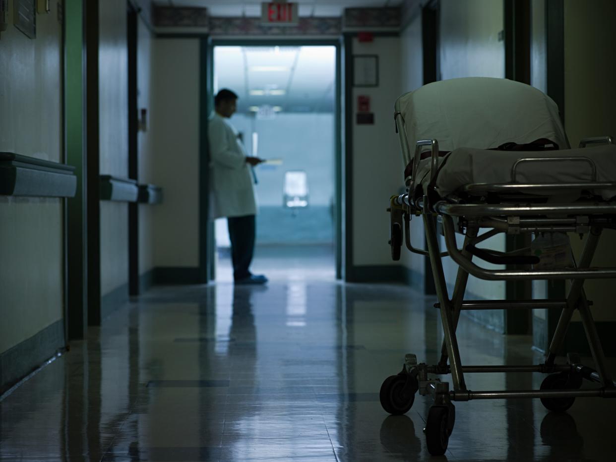 A stock image shows a doctor in a dark hospital hallway.