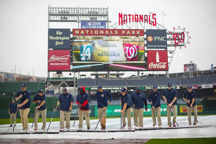 Members of the ground crew clear water off the infield tarp at Nationals Park in Washington D.C. (AP)