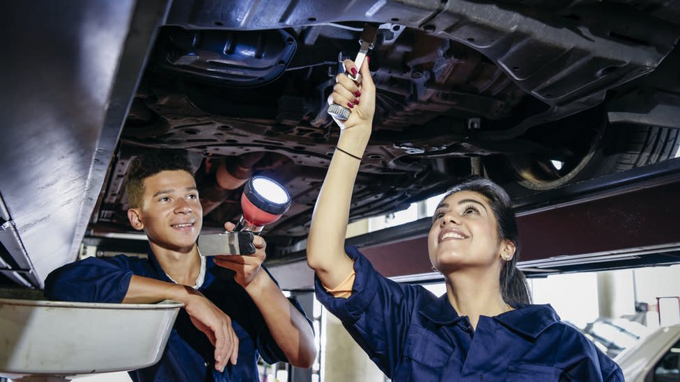 Two student mechanics repairing car