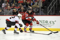 New Jersey Devils center Janne Kuokkanen (59) skates with the puck as he is checked by Ottawa Senators defenseman Thomas Chabot (72) during the first period of an NHL hockey game Monday, Dec. 6, 2021, in Newark, N.J. (AP Photo/Bill Kostroun)