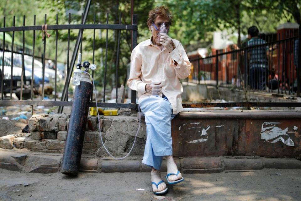 A patient, wearing an oxygen mask, sits outside Lok Nayak Jai Prakash Narayan Hospital (LNJP) in New Delhi, 22 April