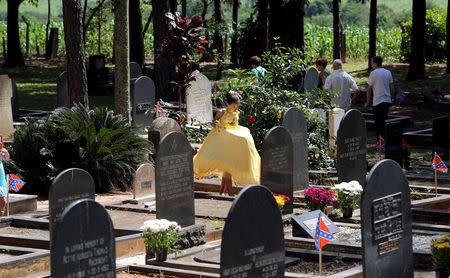 A descendant of American Southerners wearing Confederate-era dresses walks in a cemetery where American Southern immigrants are buried in tombs adorned with the confederate flag, during a party to celebrate the 150th anniversary of the end of the American Civil War in Santa Barbara D'Oeste, Brazil, April 26, 2015. REUTERS/Paulo Whitaker