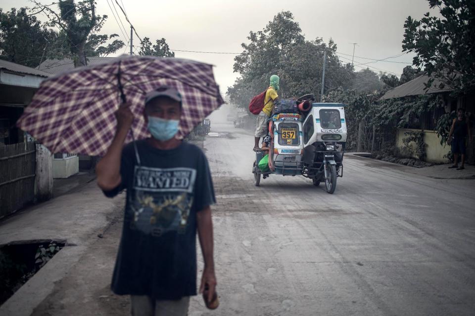 <p>FRM14. GUINOBATAN (FILIPINAS), 22/01/2018.- Varias personas se protegen con mascarillas en una carretera cubierta de ceniza tras la erupción del volcán Mayon en la localidad de Guinobatan (Filipinas), hoy 22 de enero de 2018. La agencia sismológica de Filipinas (PHIVOLCS) elevó hoy el nivel de alerta del volcán Mayon, después de que expulsara una gran nube de ceniza y ante la amenaza de una erupción mayor en las próximos horas o días. EFE/ Linus Escandor II </p>