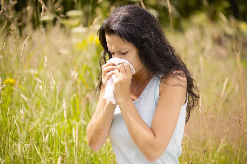 Woman blowing her nose in field
