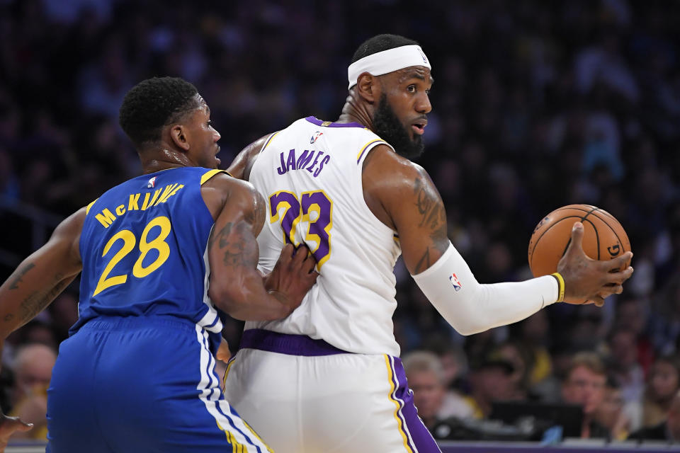 Los Angeles Lakers forward LeBron James, right, tries to move by Golden State Warriors forward Alfonzo McKinnie during the first half of a preseason NBA basketball game Wednesday, Oct. 16, 2019, in Los Angeles. (AP Photo/Mark J. Terrill)