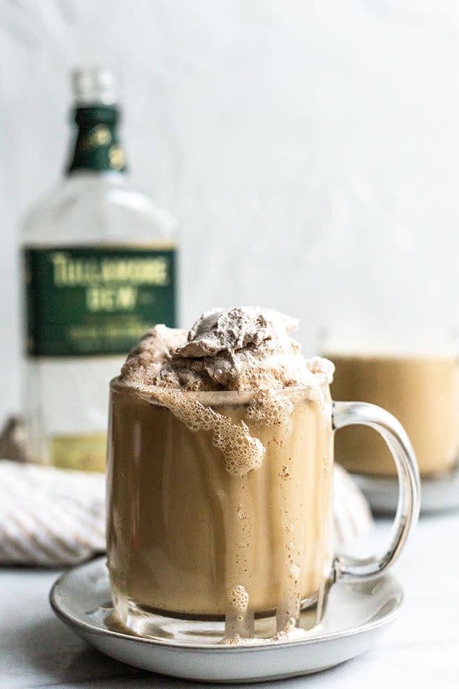 frothy irish coffee with cinnamon whipped cream in glass mug