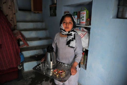 Eleven year old Afghan girl Tarana Akbari carries a tray of tea after an interview with an AFP reporter at her home in Kabul. Down a rutted dirt alley in Old Kabul, the "girl in the green dress", subject of AFP photographer Massoud Hossaini's Pulitzer-winning photograph, still has nightmares about the day a suicide bomber made her image world famous