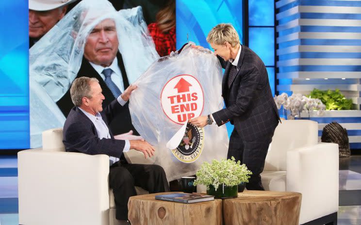 Ellen DeGeneres gives George W. Bush a poncho.