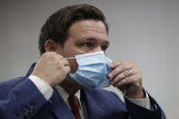 Florida Gov. Ron DeSantis puts on his mask as he leaves a news conference at Jackson Memorial Hospital, Monday, July 13, 2020, in Miami. DeSantis acknowledged Monday that the new coronavirus is spreading and urged people to take precautions such as wearing masks in public places, social distancing and avoiding crowds. (AP Photo/Wilfredo Lee)