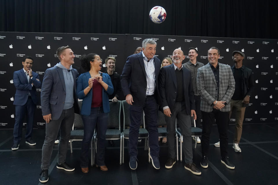 Apple senior vice president of services Eddy Cue, middle, jumps toward a soccer ball next to Major League Soccer Commissioner Don Garber, middle right, during a MLS Season Pass and Apple TV talent announcement at MLS soccer media day in San Jose, Calif., Tuesday, Jan. 10, 2023. (AP Photo/Jeff Chiu)