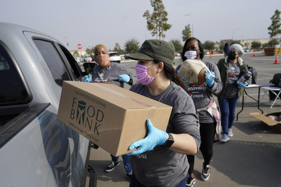Volunteers load a pickup truck at a food distribution center set up at SoFi Stadium ahead of Thanksgiving and amid the COVID-19 pandemic, Monday, Nov. 23, 2020, in Inglewood, Calif. (AP Photo/Marcio Jose Sanchez)