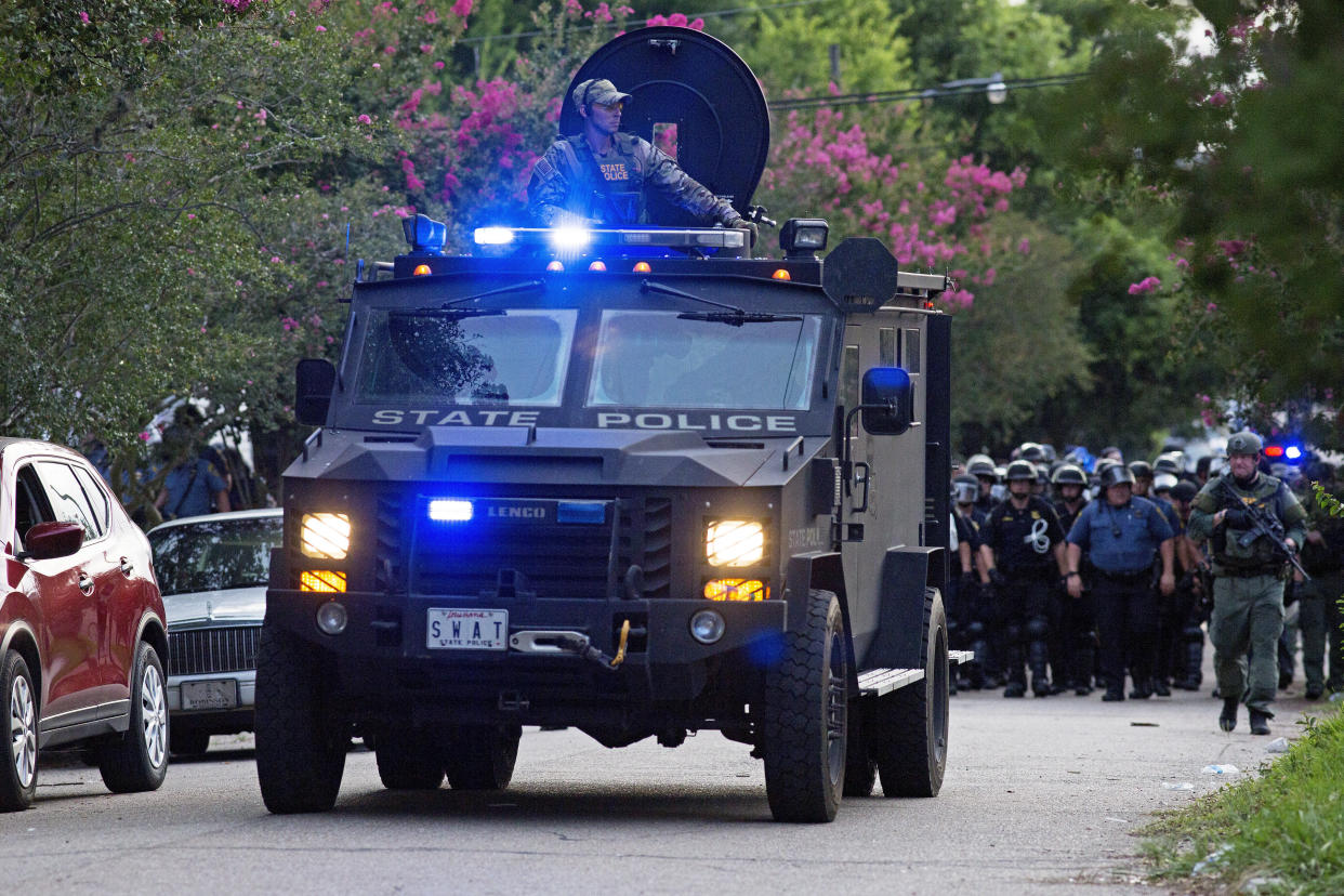 An armored police truck leads a troop of police through a residential neighborhood in Baton Rouge, La. on Sunday, July 10, 2016. After an organized protest in downtown Baton Rouge protesters wondered into residential neighborhoods and toward a major highway that caused the police to respond by arresting protesters that refused to disperse. (AP Photo/Max Becherer)