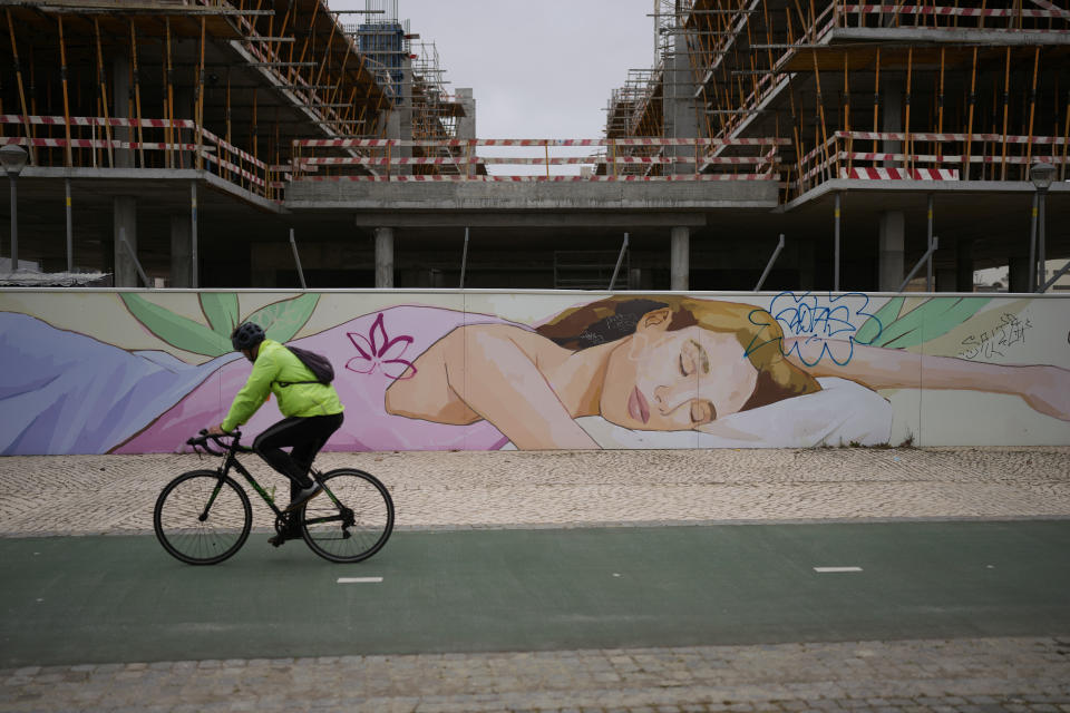 A cyclist rides by luxury buildings being erected by the Tagus river in Lisbon, Friday, March 10, 2023. Portugal’s center-left Socialist government is set to approve a package of measures to address the country's housing crisis. A growing number of people are being priced out of the property market by rising rents, surging house prices and climbing mortgage rates. (AP Photo/Armando Franca)