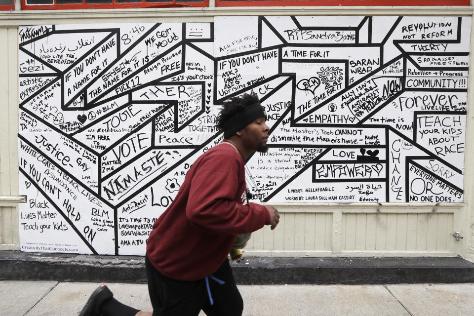 A skateboarder races past a mural on the side of a building Sunday, June 21, 2020, in Seattle, where streets are blocked off in what has been named the Capitol Hill Occupied Protest zone. Police pulled back from several blocks of the city's Capitol Hill neighborhood near the Police Department's East Precinct building earlier in the month after clashes with people protesting the death of George Floyd. (AP Photo/Elaine Thompson)