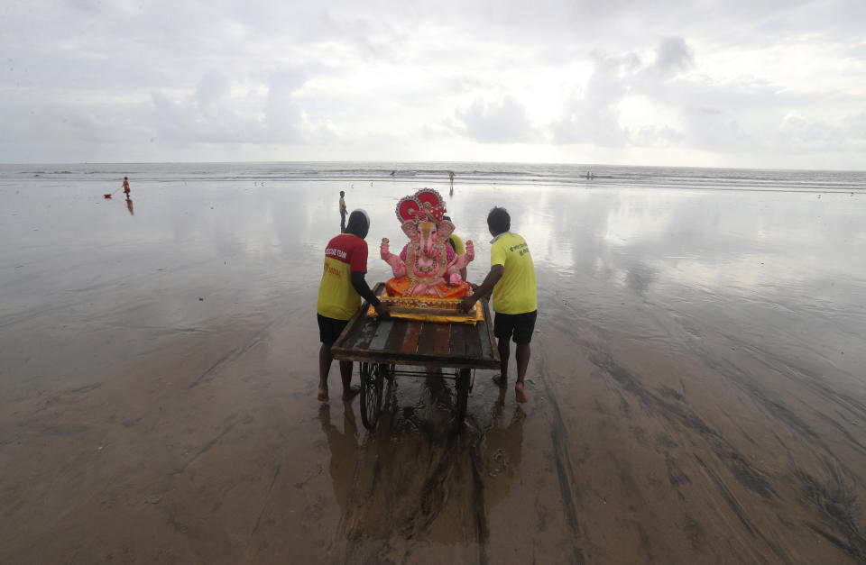 Volunteers push a hand cart as they prepare to immerse an idol of elephant-headed Hindu god Ganesha in the Arabian Sea, marking the end of the 10-day long Ganesh Chaturthi festival in Mumbai, India, Tuesday, Sept. 1, 2020. (AP Photo/Rafiq Maqbool)