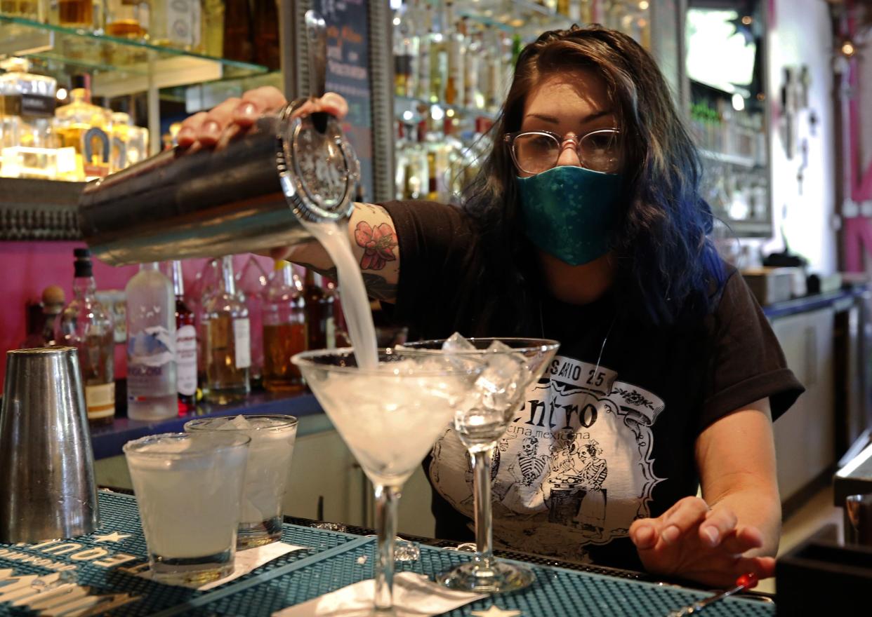 Bartender Taylor Osorio wears a face mask as she pours drinks at Centro Cocina Mexicana restaurant in Sacramento, Calif. on Friday, May 22, 2020. As part of Sacramento County's extended Stage 2 reopening plan, dine-in restaurants and retail stores were allowed to open at noon Friday after being closed for several months due to the coronavirus pandemic.