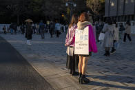 A couple of women advertises for PCR testing for COVID-19 near the front entrance gate for Maiji Jingu Shinto Shrine Friday, Jan. 1, 2021, in Tokyo, as people arrive any the shrine to pray for good fortune in the new year. Meiji Shrine in downtown Tokyo, which attracts millions of people every year during New Year holidays and is usually open all night on New Year's Eve, was closed its doors from 4 p.m. on Dec. 31 to 6 a.m. this year to avoid cluster. This was the first time the popular shrine closed its door on New Year's Eve night in 74 years. (AP Photo/Kiichiro Sato)
