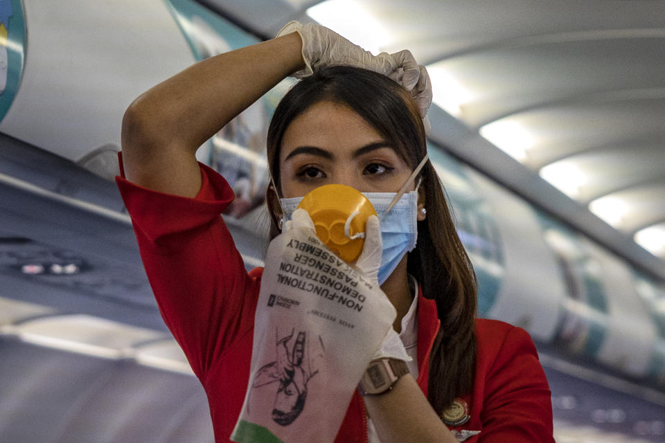 INCHEON, SOUTH KOREA - MARCH 10: A flight attendant is seen wearing a facemask and gloves as protection from COVID-19 while demonstrating safety procedures aboard an AirAsia flight bound for Manila, Philippines, at Incheon International Airport on March 10, 2020 in Incheon, South Korea. According to the Korea Centers for Disease Control and Prevention, 131 new cases have been reported, with the death toll rising to 54. The total number of infections in the nation tallies at 7,513. (Photo by Ezra Acayan/Getty Images)