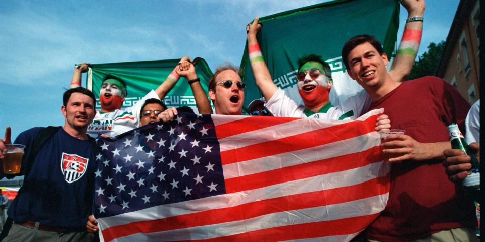 Fans hold up an American flag while standing with fans with Iranian face paint before a World Cup match in 1998.