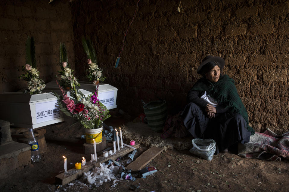 En imagen del 15 de agosto de 2018, Marta Tineo Espinosa se sienta al lado de los féretros de sus parientes, que murieron a manos de las guerrillas del grupo Sendero Luminoso y el ejército peruano en 1984, en el día de su entierro en Tantana, en la provincia de Ayacucho. Perú entregó los restos de 14 personas consideradas desaparecidas desde hace tres décadas gracias a una ley pionera en América Latina que agiliza la identificación y entrega de cuerpos de asesinados durante el conflicto armado interno de 1980 a 2000. (AP Foto/Rodrigo Abd)