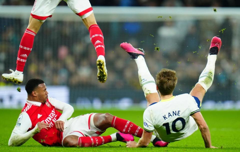 Harry Kane of Tottenham Hotspur falls to the turf after a challenge from Gabriel of Arsenal