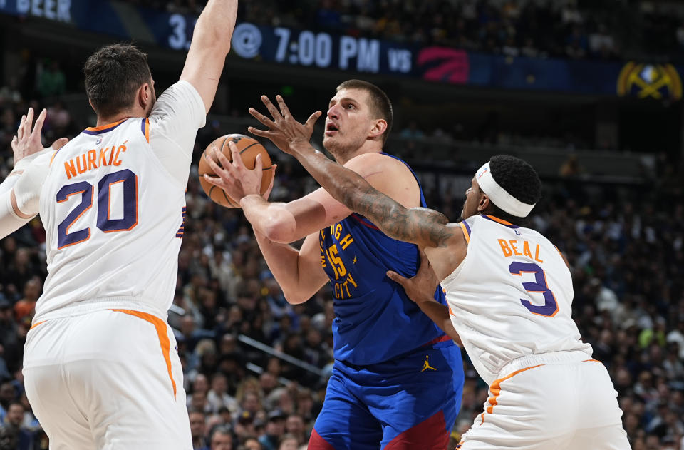 Denver Nuggets center Nikola Jokic, center, is defended by Phoenix Suns center Jusuf Nurkic, left, and guard Bradley Beal during the second half of an NBA basketball game Tuesday, March 5, 2024, in Denver. (AP Photo/David Zalubowski)