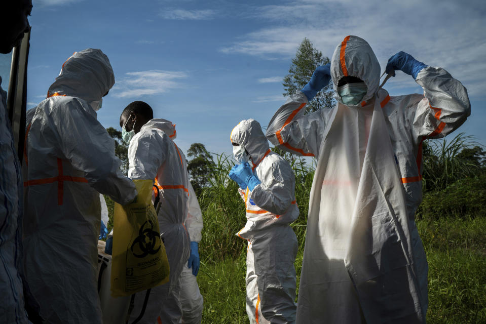 In this Sunday, July 14, 2019 photo, burial workers put on protective gear before carrying the remains of Mussa Kathembo, an Islamic scholar who had prayed over those who were sick, and his wife, Asiya, to their final resting place in Beni, Congo. Both died of Ebola. (AP Photo/Jerome Delay)