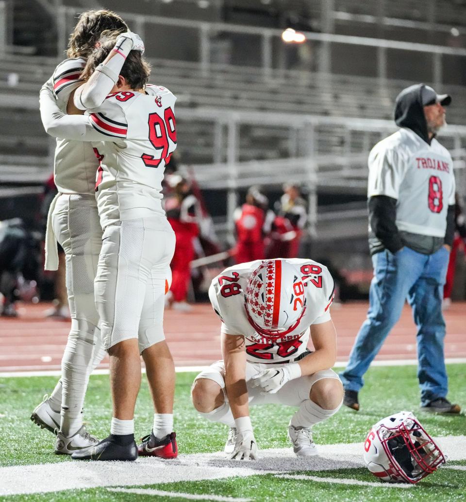 Center Grove Trojans defensive back Connor Cannon (28) kneels down in disappointment as Center Grove Trojans Tyler Schruben (99) hugs a teammate on Friday, Nov. 17, 2023, after the IHSAA semi state championship game at Ben Davis High School in Indianapolis. The Ben Davis Giants defeated the Center Grove Trojans in overtime, 37-34.