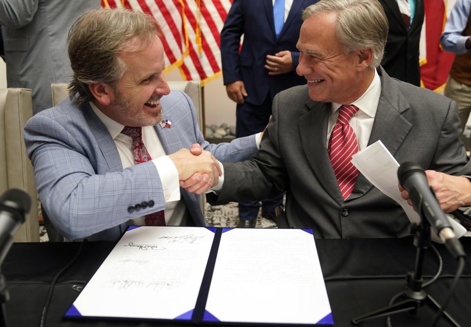 Gov. Greg Abbott and Sen. Bryan Hughes, R-Mineola, shake hands in 2021 after Abbott signed a bill tightening voting laws. After that bill decreased penalties for illegal voting to a misdemeanor, Hughes has come back this year with a new bill raising the penalty to a felony.