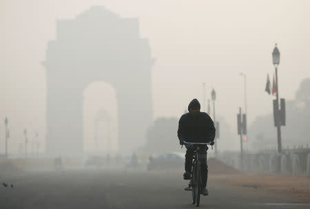 A man rides his bicycle in front of the India Gate shrouded in smog in New Delhi, December 26, 2018. REUTERS/Adnan Abidi/Files