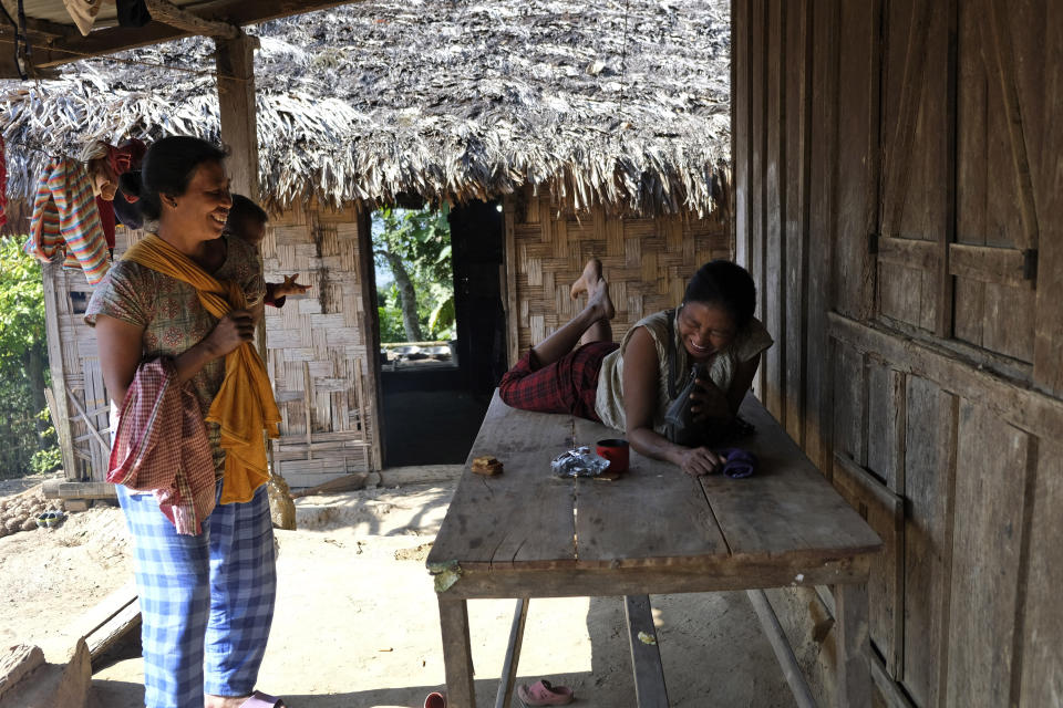 Awat Wangshu, right, laughs with a neighbour outside her home in Oting village, in the northeastern Indian state of Nagaland, Thursday, Dec. 16, 2021. Awat's 23-year-old son Manpeih was killed by Indian army soldiers on Dec. 4, when he went out as part of a rescue team in search of 8 missing villagers, six of whom had already been killed by the soldiers. Neighbours are usually around to comfort Awat. Grief is shared in the village, even if each villager processes loss in his or her own way. There are friendships and marriages and lifetimes that link the people here. (AP Photo/Yirmiyan Arthur)