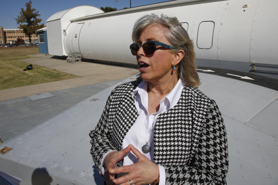 Stacey L. Zinke-McKee, a medical-research official at the Federal Aviation Administration facility in Oklahoma City, answers a question in front of an aircraft simulator Thursday, Oct. 17, 2019, in Oklahoma City. Federal researchers, using 720 volunteers in Oklahoma City, will test whether smaller seats and crowded rows slow down airline emergency evacuations. (AP Photo/Sue Ogrocki)
