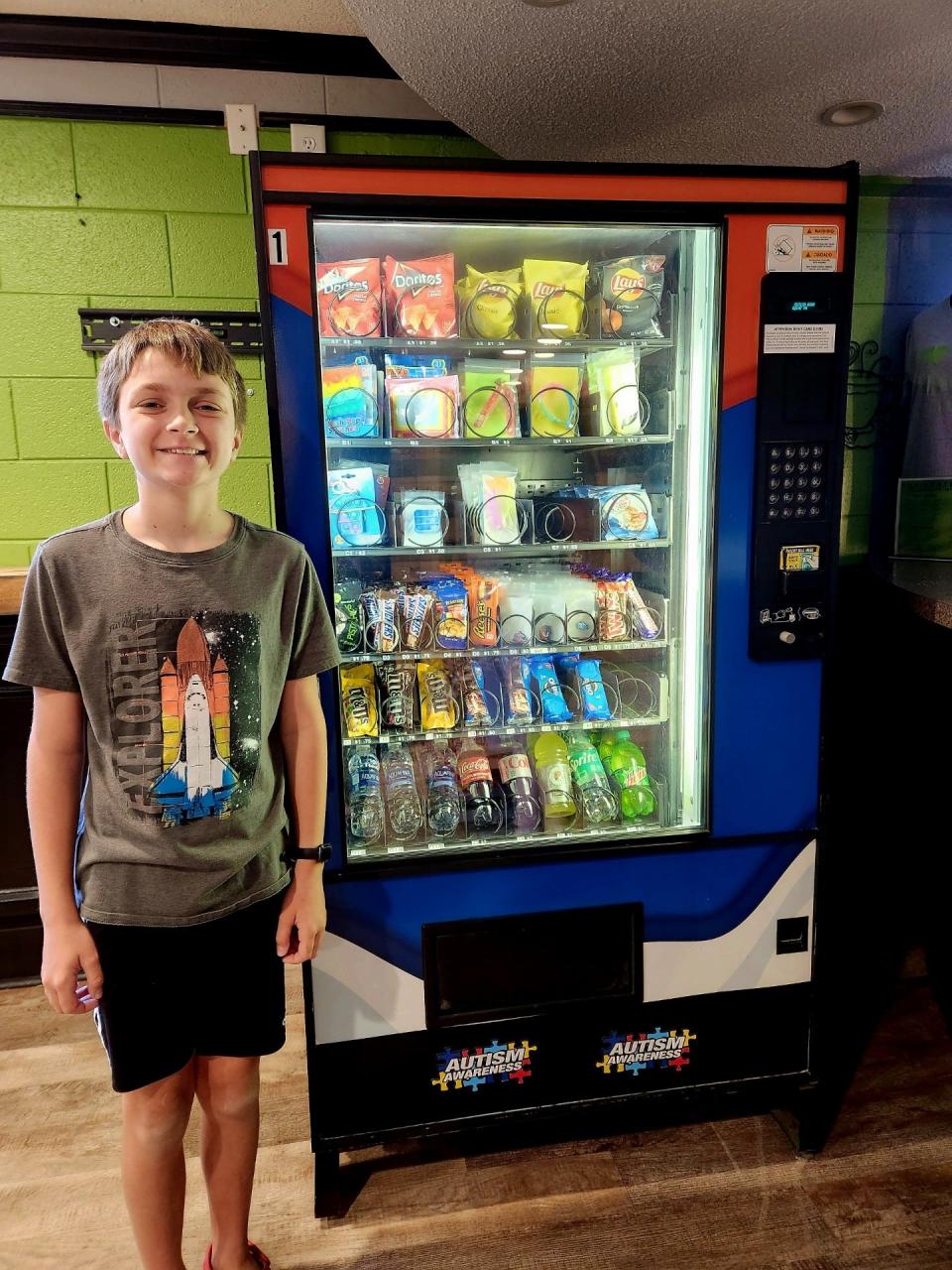 Carter stands with a vending machine that he hopes will help raise funds to pay for his special needs education at   Fayetteville's only autism school.