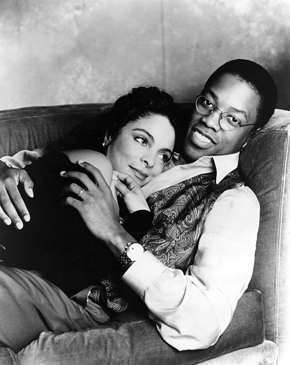 Two characters from "The Cosby Show," Clair and Cliff Huxtable, affectionately seated together on a couch