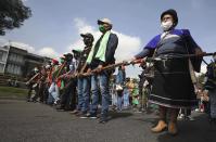 Members of the Indigenous Guard get ready to march against the government in Bogota, where thousands traveled in a caravan from Cali, Colombia, Monday, Oct. 19, 2020. The leaders of the indigenous communities say they are mobilizing to reject massacres, assassinations of social leaders, criminalization of social protest, to defend their territory, democracy and peace, and plan to stay in the capital for a nationwide protest and strike on Oct. 21. (AP Photo/Fernando Vergara)