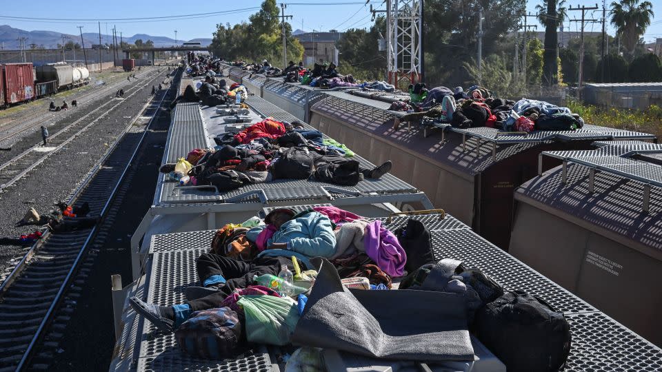 Migrants rest on railroad cars as they wait for a freight train to travel to the US border, at a rail yard in Chihuahua, Mexico, on December 26. - Raul Fernando Perez/Reuters