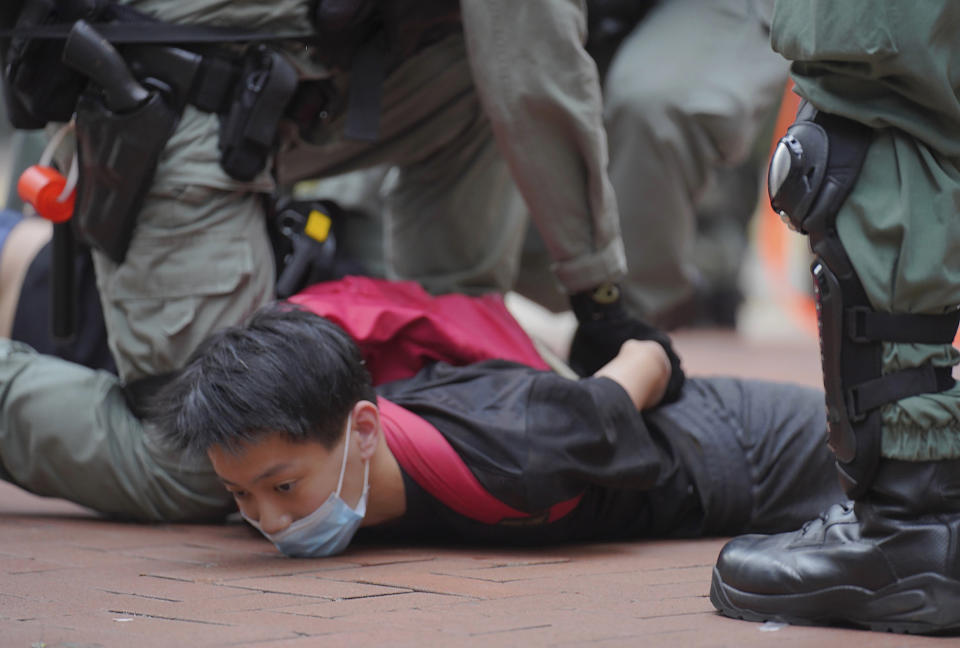A protester is detained by riot police during a demonstration against Beijing's national security legislation in Causeway Bay in Hong Kong, Sunday, May 24, 2020. Hong Kong police fired volleys of tear gas in a popular shopping district as hundreds took to the streets Sunday to march against China's proposed tough national security legislation for the city. (AP Photo/Vincent Yu)