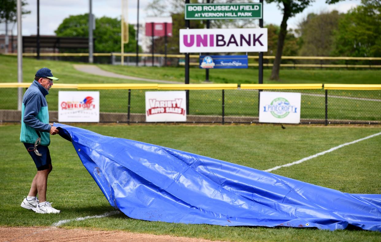 As part of his many tasks to make the Vernon Hill softball field one of the best in the state, Worcester's Bob Rousseau drags a protective rain tarps before a recent St. Paul junior varsity game.
