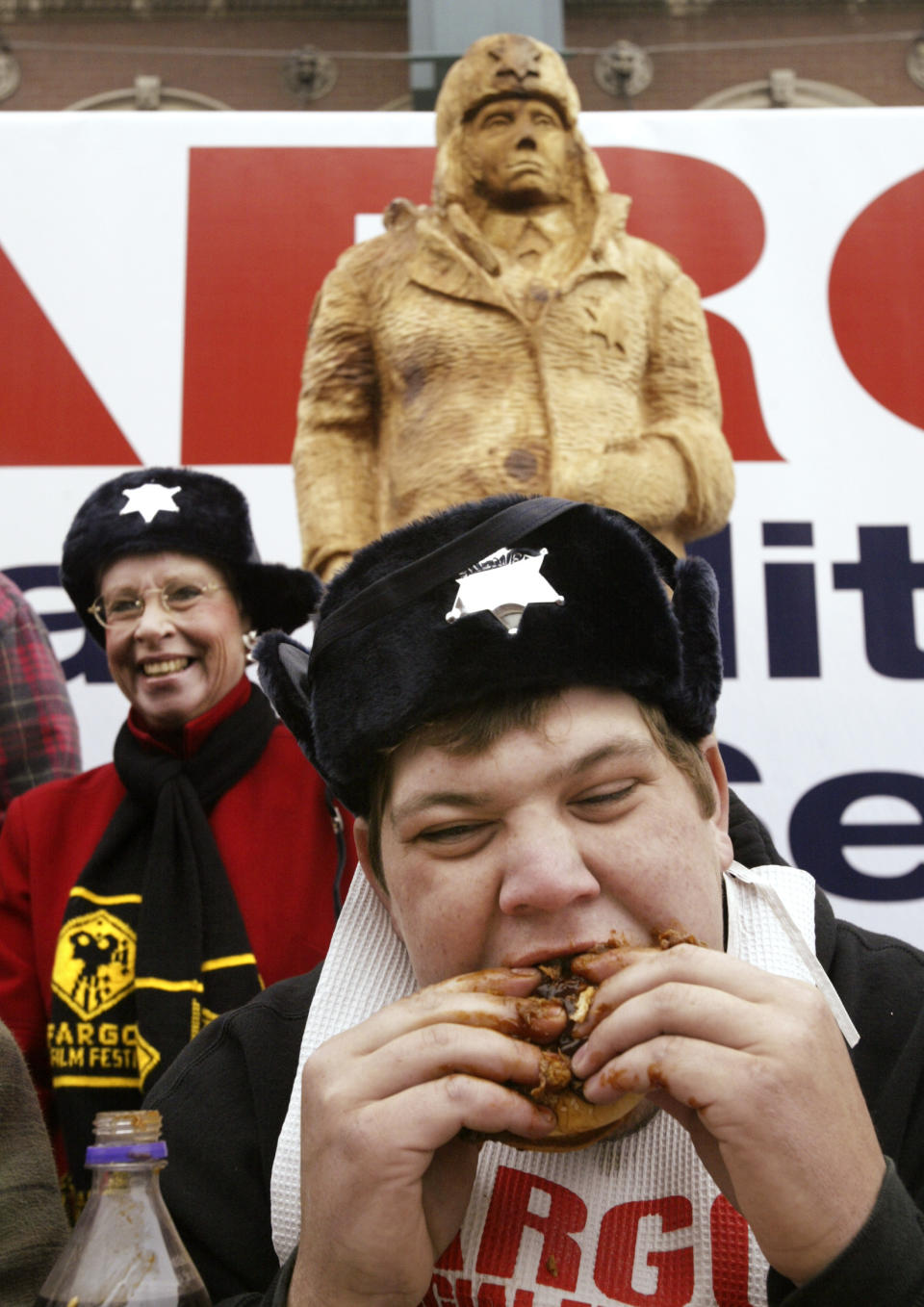 In this photo taken Sept. 25, 2003, Fargo Theatre executive director Margie Bailly looks on while Logan Kling of Fargo does his best to consume a roast beef sandwich during an eating contest held outside the theater in Fargo, N.D. When the movie Fargo debuted in 1996, many residents in the North Dakota city were not fans of the film’s dark humor, not to mention the heavy accents. But the fame and cash from the movie eventually brought many Fargo residents around. Now, 16 years later, Fargo awaits the debut of a new cable television show by the same name. And many residents are less apprehensive about how their hometown will be portrayed this time around. (AP Photo/The Forum, Darren Gibbins)