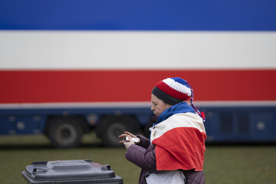 A woman wearing the Dutch flag upside-down disposes of a wrapper as thousands of demonstrators joined an anti-government protest by farmers' organizations in The Hague, Netherlands, Saturday, March 11, 2023. The protest comes days before Dutch provincial elections on March 15, in which a party representing farmers' interests is expected to perform well. (AP Photo/Peter Dejong)