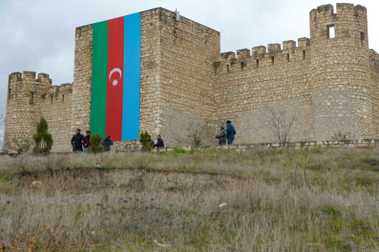 Un immense drapeau azerbaïdjanais couvre l'une des murailles du château de Shahbulag, à l'extérieur d'Agdam, alors que des réfugiés de retour visitent leurs anciennes maisons (AFP/Tofik BABAYEV)