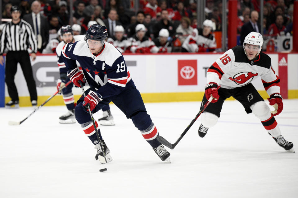 Washington Capitals center Nicklas Backstrom (19) skates with the puck past New Jersey Devils left wing Jimmy Vesey (16) during the first period of an NHL hockey game, Saturday, March 26, 2022, in Washington. (AP Photo/Nick Wass)